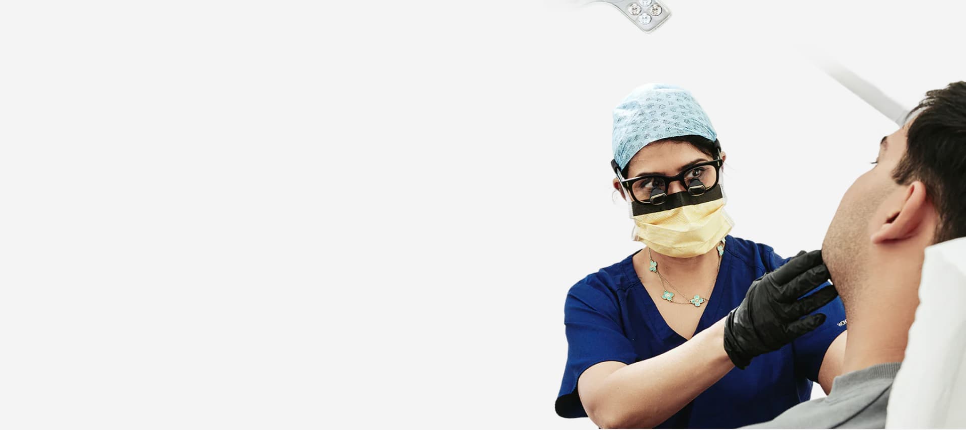 A surgeon in scrubs examining a patient's face