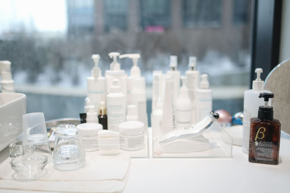 A bathroom shelf crowded with skincare bottles, serums and jars